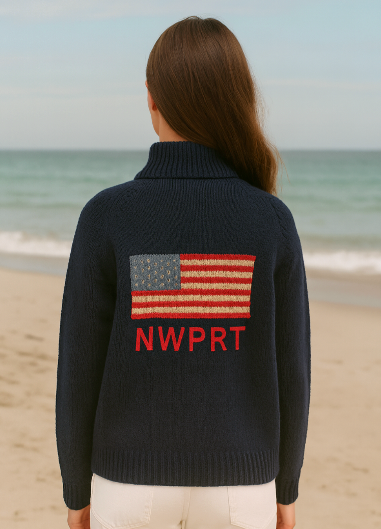 Person wearing a navy sweater with an American flag and 'NWPRT' text on a beach.